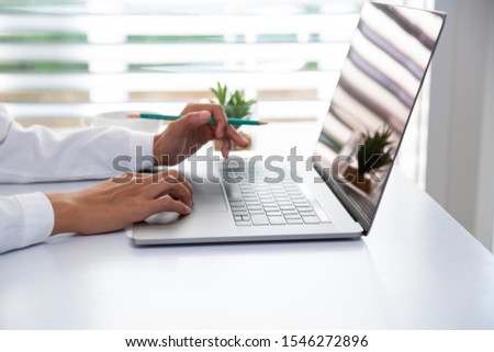 Businesswoman or accountant. Work in a creative and modern room.The laptop is on the table.  Rest their hands on a laptop with a pencil Business planning work concepts Hurry and clear the delivery.