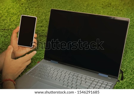 Man holds the smartphone with black screen lying on the carpet near the black-screened laptop. Digital devices for domestic internet access. Usage of cellphone and portable computer at home. Services