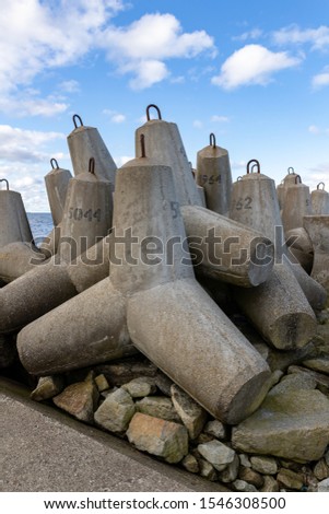 Concrete fortifications in the seaport. Tetrapods stacked on the edge of a breakwater in Central Europe. Autumn season.