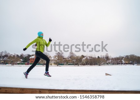 Picture of young athlete woman running in winter park