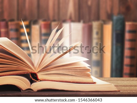 Old open book on a bookshelf background. Royalty-Free Stock Photo #1546366043