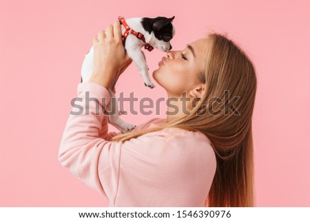 Cute lovely girl playing with her pet chihuahua isolated over pink background