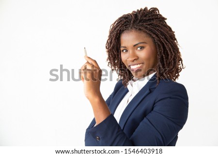 Happy cheerful student holding pen, looking at camera, smiling. Young African American business woman standing isolated over white background. Education concept