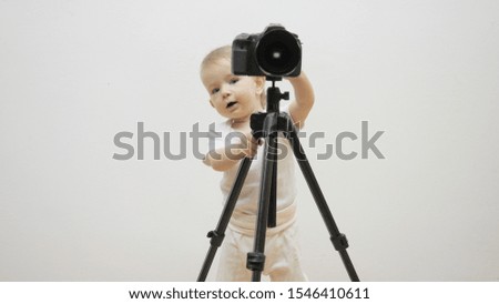 Little child taking pictures with camera on tripod, happy baby discovery