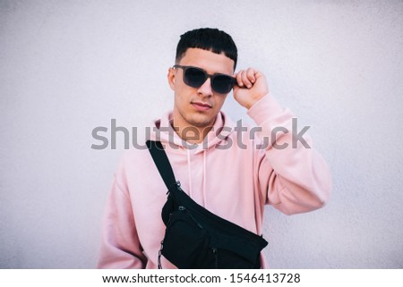 City portrait of handsome hipster guy wearing pink blank hoodie with black waist bag with space for your logo or design. Mockup for print