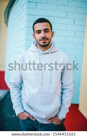 City portrait of handsome hipster man with beard wearing gray blank hoodie or sweatshirt with space for your logo or design. Mockup for print