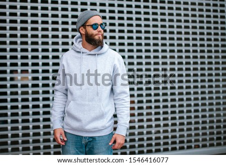 City portrait of handsome hipster guy with beard wearing gray blank hoodie or sweatshirt with space for your logo or design. Mockup for print