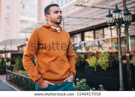 City portrait of handsome hipster guy with beard wearing brown blank hoodie or hoody with space for your logo or design. Mockup for print