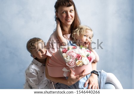 Mom with two children and a bouquet of flowers in a pink box.