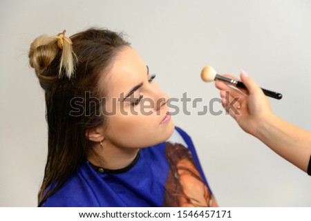 Studio photo of the work of a makeup artist by a hairdresser beautician. Creating beautiful makeup and hairstyles, rejuvenating the skin of the face. The professional is working with special tools.