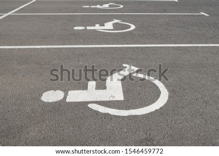 Disabled parking sign in a parking space. Symbol of a person in a wheelchair on the pavement, drawn by white paint. State policy of social responsibility.