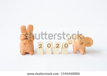 Happy New Year 2020, letter on wooden cube with lovely rabbit and elephant clay friend isolate on white background, smiling welcome to year 2020