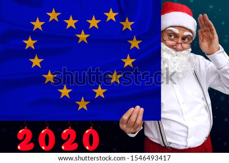Santa Claus with a beard holds a beautiful photo of a stylized European Union flag with a festive date 2020, the concept of tourism, the new year, economic and political prospects