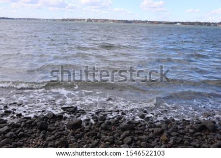 the ocean, with rocks at the coast and a city in the distance