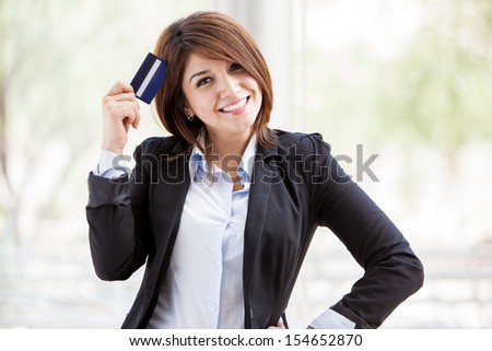 Cute young bank representative on a suit holding a business card in her hand and smiling