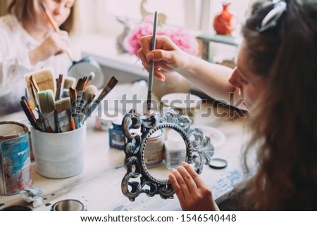 girl paints the frame with a brush. handwork. creation