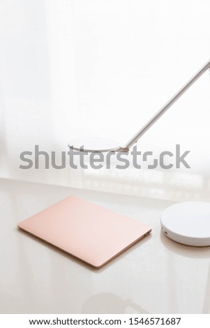 Modern rose gold laptop and white lamp on white desk