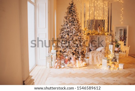 warm cozy evening in luxury Christmas room golden interior design,window Xmas tree decorated lights gifts toys, candles, lanterns, garland lighting fireplace.holiday living room. New year holidays
