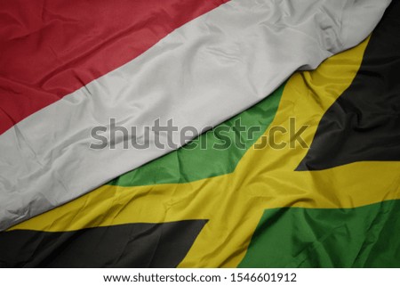 waving colorful flag of jamaica and national flag of indonesia. macro