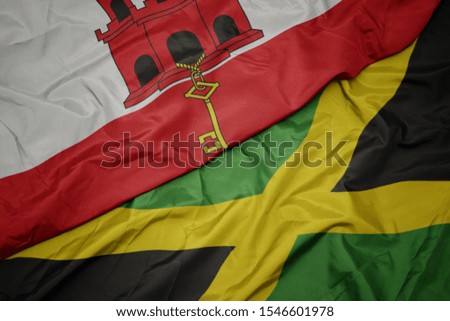 waving colorful flag of jamaica and national flag of gibraltar. macro