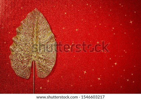 Christmas red background with gold leaf, copy space, text place,  flat lay. Christmas or New Year floral red frame with golden lace leaf, gold metallic glittering Xmas card, copy space.