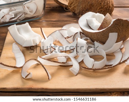 Close up view of dried coconut chips in on baking paper in a glass pan and on cutting board with coconut shells Royalty-Free Stock Photo #1546631186