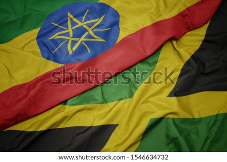 waving colorful flag of jamaica and national flag of ethiopia . macro