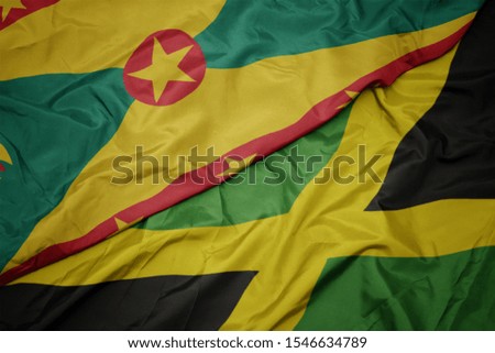 waving colorful flag of jamaica and national flag of grenada. macro