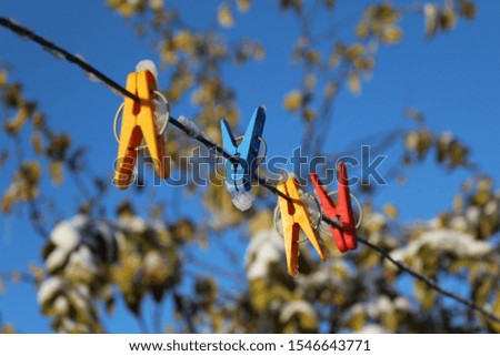 photo colored clothespins.they are attached to a clothesline.rope on the street in the yard.against a beautiful, bright blue sky.