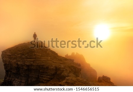a man at a sunset in the foggy mountains
