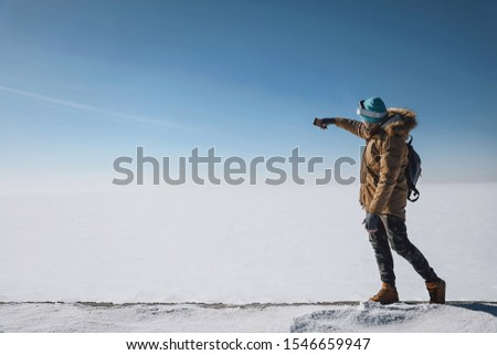a guy in a snow field stands and takes a picture of himself on the phone
