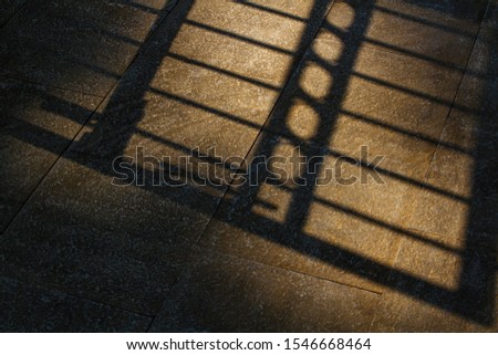 A photograph of park gate silhouette on the floor in the morning