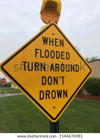 A sign warns drivers of dangerous flood conditions while rhyming