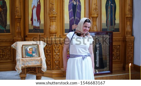 Parishioner in Orthodox Church. Women with headscarf smiling a looking at candle