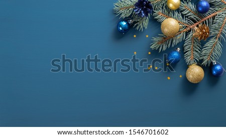 Christmas composition with green pine twigs, gloden and blue decorations, confetti on blue background with copy space. Top view, Flat lay. Xmas banner mockup, vintage postcard template