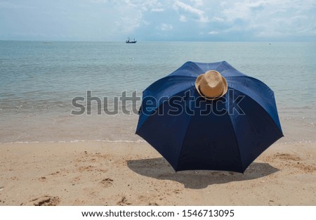 Blue umbrellas and brown hats put on unseen beaches The background is a blue sea.Background beach.copy space for text.