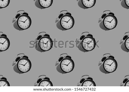 Many black classic style alarm clock with hard shadow isolated on background. Black and white smile time concept. Pattern