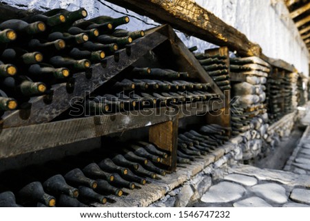 Stacked of old bottles in the cellar, wine in dark bottles covered with dust