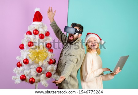 Bearded man in virtual 3D glasses at christmas. New Year, Christmas, future and technology concept. 3d technology, virtual reality, entertainment. Virtual reality mask. Woman in santa hat with laptop.