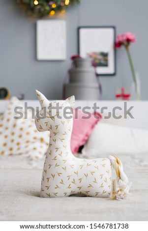 Soft toy or pillow in the form of a unicorn on the bed, decorated for Christmas
