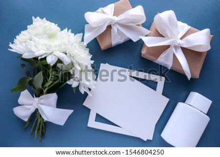 greeting card design. bouquet of white chrysanthemums on a blue background, gift box and envelope. wedding invitation. flat lay. view from above