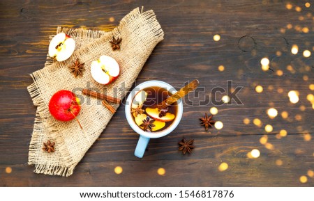 Christmas background. Hot mulled wine with ingredients in cup on wooden background. The concept of celebration and cooking warming drinks.Top view, close up, copy space