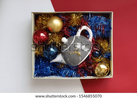 box with colorful tinsel and Christmas balls on a red and white background. the view from the top
