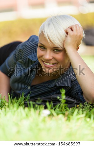Photo of blonde smiling woman laying on a grass field