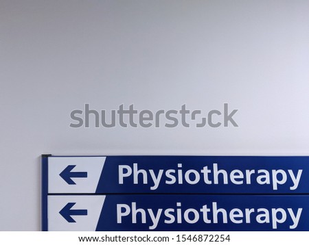 Dark blue, directional, physiotherapy signs attached to a white wall in a health centre