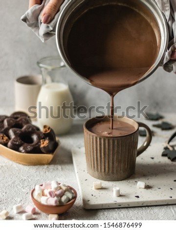 Cup of hot chocolate poured on bright background with cookies and marshmllow