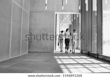 Black and white photo of business people walking while discussing plans before meeting in office corridor