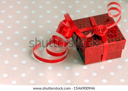 On a light background lies a red gift box with ribbon