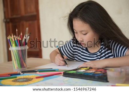 little girl with brush painting on table in School, education, cut girl painting in at her home. Selective focus and small depth of field, Painting with watercolor, drawing, Creativity concept.