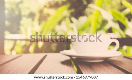 Blur background coffee cup on wood table in garden. - vintage style effect picture